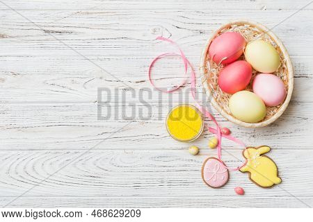 Colorful Easter Cookies In Basket With Multi Colors Easter Eggs On Colored Background . Pastel Color