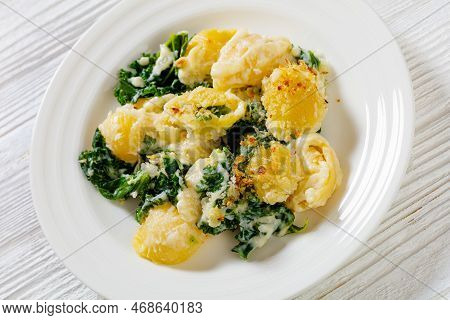 Portion Of Cheesy Baked Shell Pasta With Green Leafy Kale Topped With Crispy Breadcrumbs On Plate On