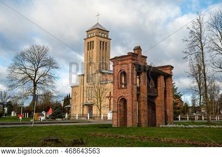 Old Catholic Church And Red Brick Gates In City Akniste, Latvia. Aknistes Visual Identity Symbol.