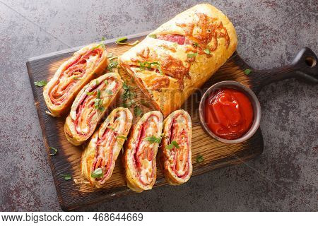 Delicious Pizza Stromboli Roll Stuffed With Salami Sausage And Mozzarella Cheese Close-up On A Woode