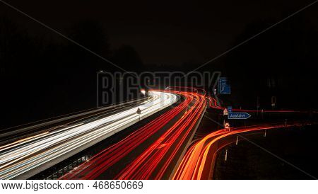 Long Exposure, White Front And Red Rear Lights As Car Light Strips At Night, German Text For Exit An
