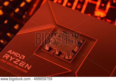 A Close-up Of An Amd Ryzen 9 3900X Processor In A Packaging Box With Backlit Keyboards In The Backgr