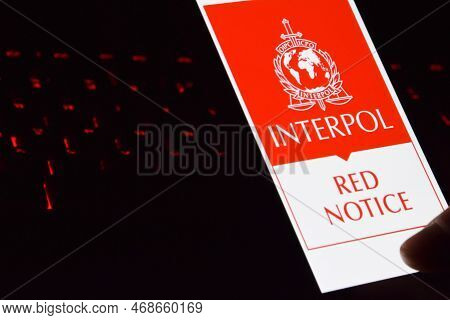 Person Holding Smartphone With Interpol Logo Displayed On Screen.