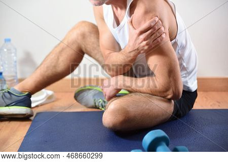 Detail Of Man Doing Sports With Shoulder Pain Holding Himself With His Hand Sitting On A Mat. Side V