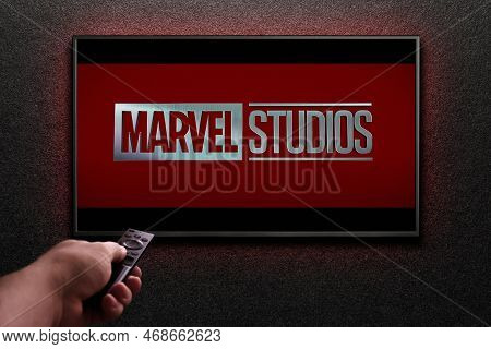 Man Turns On Tv With Remote Control. Tv Screen Playing Marvel Studios Movie. Moscow, Russia - Januar