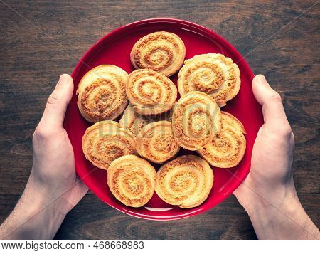 Deliciously Crisp Flaky Cookies In The Shape Of A Spiral On A Red Plate In Human Hands, Selective Fo
