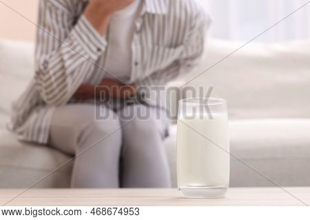 Woman Suffering From Lactose Intolerance At Home, Focus On Glass Of Milk. Space For Text