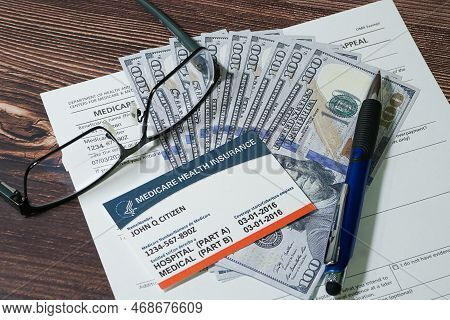 Medicare Card, Application Form And Cash With Eyeglasses And Pen.