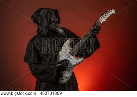 A Man In A Plague Doctor Costume Plays The Guitar Emotionally On A Red Background