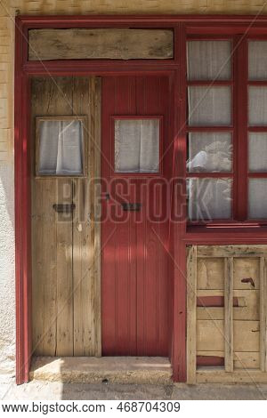 Old Wooden Front Doors - One Red And One Plain In Greece
