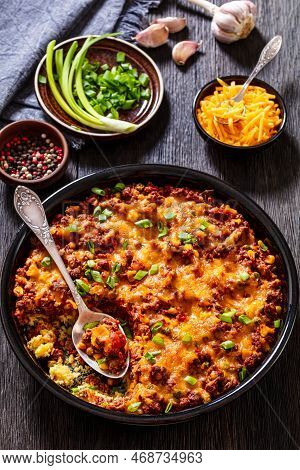 Cajun Beef Cornbread Casserole Topped With Melted Red Cheddar Cheese And Scalions In Baking Dish On 