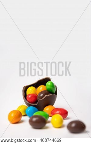 Cracked Chocolate Easter Egg Full Of Colorful Small Round Candies On A White Background With Colorfu