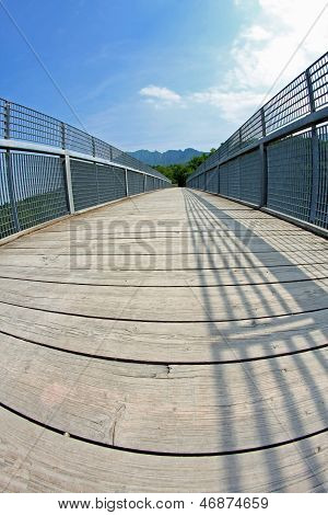 Long Bridge With A Wooden Walkway And Handrail Made Of Galvanized Steel