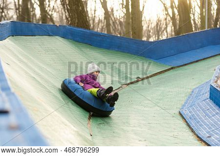 Active Girl Sliding Down The Hill On Snow Tube. Cute Little Happy Child Having Fun Outdoors In Winte
