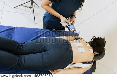 Professional Physiotherapist Electrostimulating A Lying Patient. Electrode Treatment To Patient Lyin