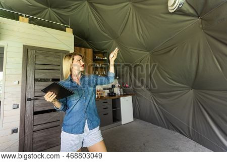 Woman With Tablet Turning On Ventilation System As A Recuperator For Fresh Indoor Air Quality, Smart