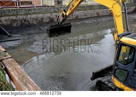 Removing Sedimentary Sludge From The Bottom Of A Pond Or A Swimming Lake In The Village. The Muddy W