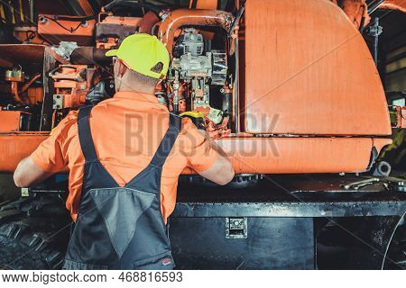 Excavator Mechanic Taking Closer Look Into The Machine Diesel Engine. Heavy Duty Equipment Repairs. 
