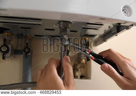 Man Repairing Gas Boiler With Waterpump Plier, Closeup