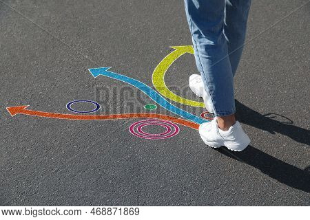 Choice Of Way. Woman Walking Towards Drawn Marks On Road, Closeup. Colorful Arrows Pointing In Diffe