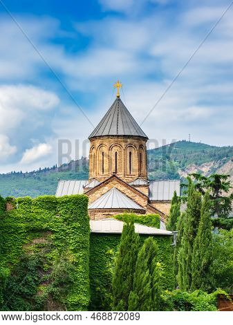 Domes Of Metekhi Church Among Green Cypress Trees In Old Town Of Tbilisi, Georgia. Georgian Orthodox