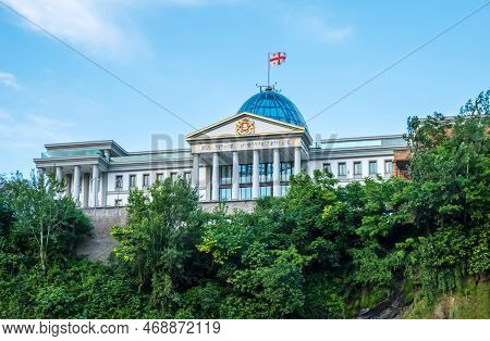 Presidential Palace In Tbilisi, Georgia With Waving Georgian Flag Behind Green Trees. Palace Of Stat
