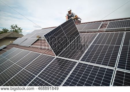 Man Technician Mounting Photovoltaic Solar Moduls On Roof Of House. Mounter In Helmet Installing Sol