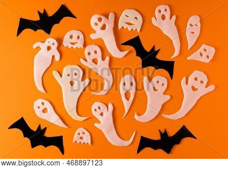 White Ghosts And Bat Craft For Halloween Party. Wrapping Paper Ghost On Orange Background Top View. 