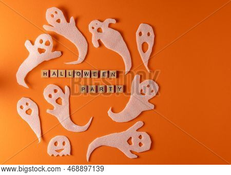 White Ghosts Craft For Halloween Party. Wrapping Paper Ghost On Orange Background Top View. Cartoon 