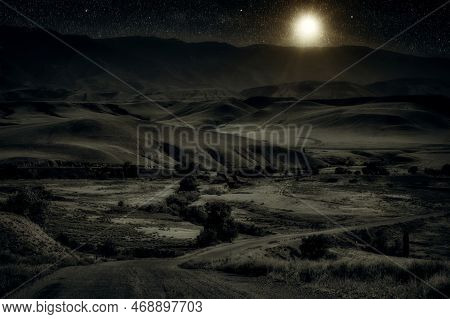 Kazakhstan Landscape Of Steppe And Stone Mountains Along The Road At Night With Moon And Falling Sta