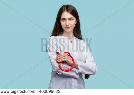 Female Intern Doctor Posing With Arms Crossed Looking At Camera On Blue Background Studio. General P