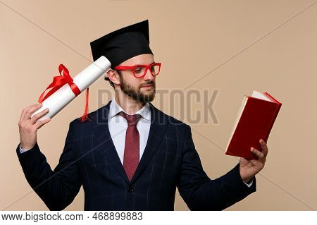 Male Graduate Wears Suit Tie Graduation Cap And Red Eyewear Hold Book Read Scientific Literature. Pr