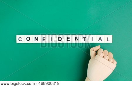 Wooden Hand With The Word Confidential Alphabet Letters. The Concept Of Difficult Things. Confidenti