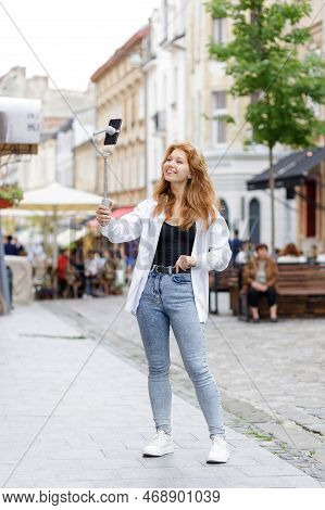 Young Redheaded Beautiful Woman Walking And Using Her Mobile Phone