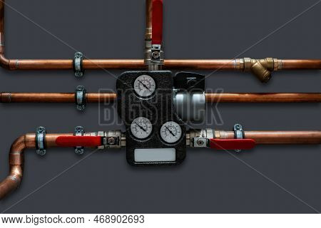 Copper Pipes And Thermoregulator With Valves On A Grey Wall. Close Up..