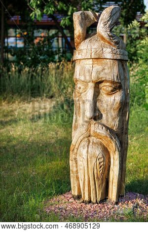 Wooden Carved Statue Of The Head Of An Ancient Ukrainian Warrior On A Blurred Background Of A Green 