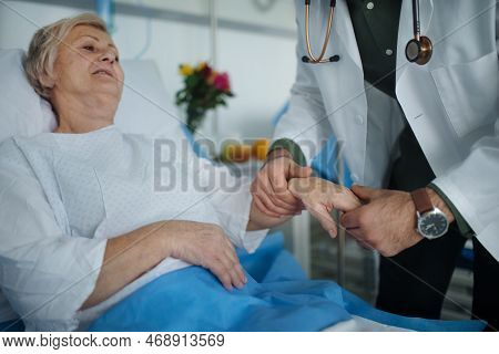 Young Doctor Chcecking Blood Presure To Senior Patient.