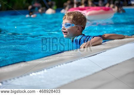 Boy In A Bathing Suit And Goggles Swims Merrily In A Warm Outdoor Pool With Clear Clear Water. A Chi