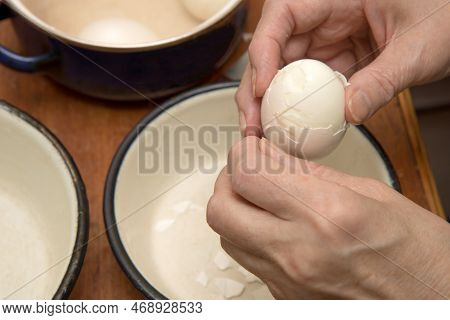 Hands Of A Middle-aged Woman Peeling A Boiled Egg From The Shell