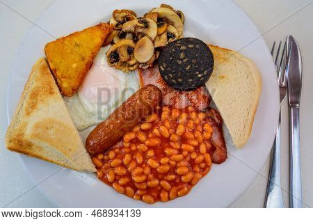 White Board With Full English Breakfast With Bacon, Fried Egg, Beans, Tomato, Roasted Sausage, Black