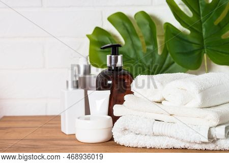 Spa Products In The Bathroom. Bottle Of Soap, Cosmetics And White Towels In White Bathroom.