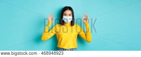 Covid-19, Social Distancing And Pandemic Concept. Smiling Confident Asian Woman In Medical Mask Show