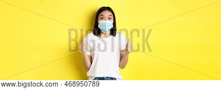Covid-19, Quarantine And Social Distancing Concept. Cheerful Asian Woman In Medical Mask And White T