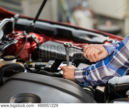 Female Auto Mechanic Unscrewing A Nut To Replace A Car Spark Plug.