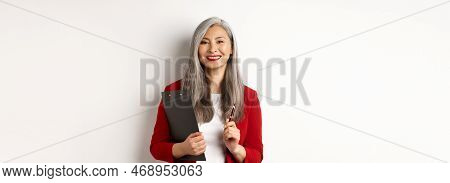 Successful Asian Lady Boss In Red Blazer, Holding Clipboard With Documens And Pen, Working And Looki