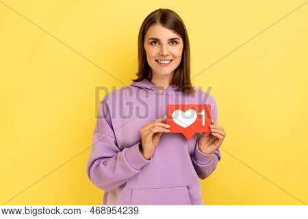 Cheerful Carefree Woman Holding Heart Like Icon Of Social Media, Notification Button To Follow, Subs