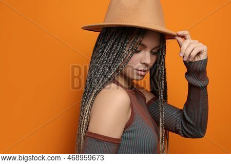 Beautiful Woman With Long African Braids And Hat On Orange Background, Space For Text