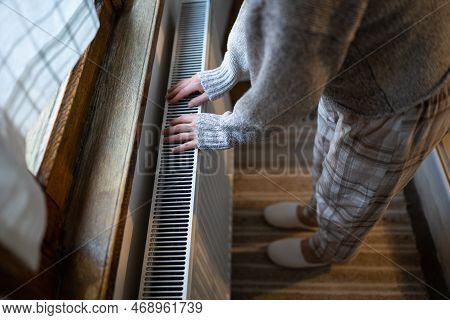 Closeup Of Woman In Woolen Sweater Wants To Keep Warmth In Apartment. Lady Puts Hands On Room Centra
