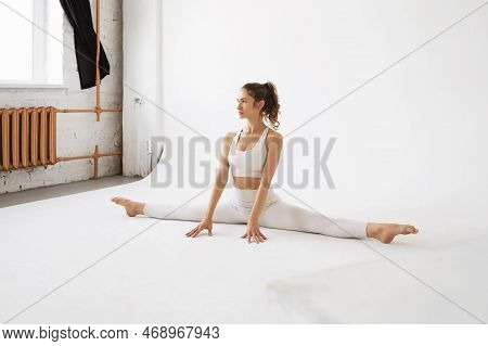 Young Athletic Woman Practicing Yoga, Performs Samakonasana Exercise, Transverse Twine, Trains In Wh
