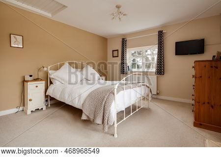Kennett, Suffolk, England - March 1 2019: Traditional Furnished Cottage Bedroom With Wall Mounted Te